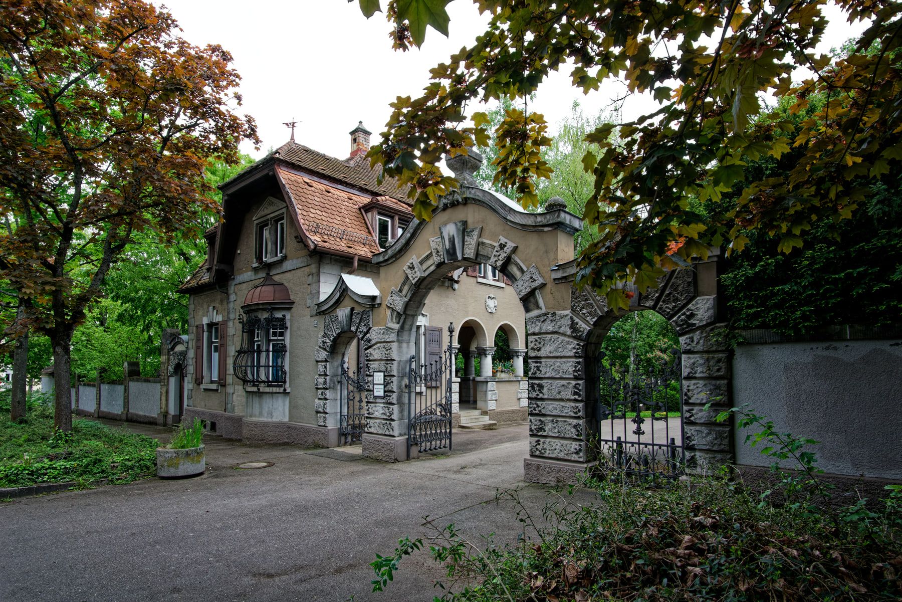 Geschwungenes dreiteiliges Portal mit schmiedeeisernen Toren vor dem Dienstgebäude auf Bergfriedhof Stuttgart