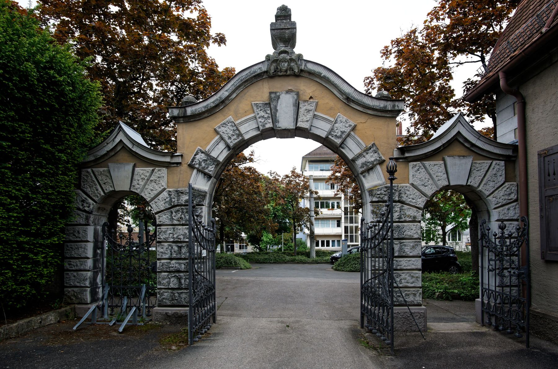 Frontalansicht des dreiteiligen Steinportals mit geöffneten schmiedeeisernen Toren auf Bergfriedhof Stuttgart