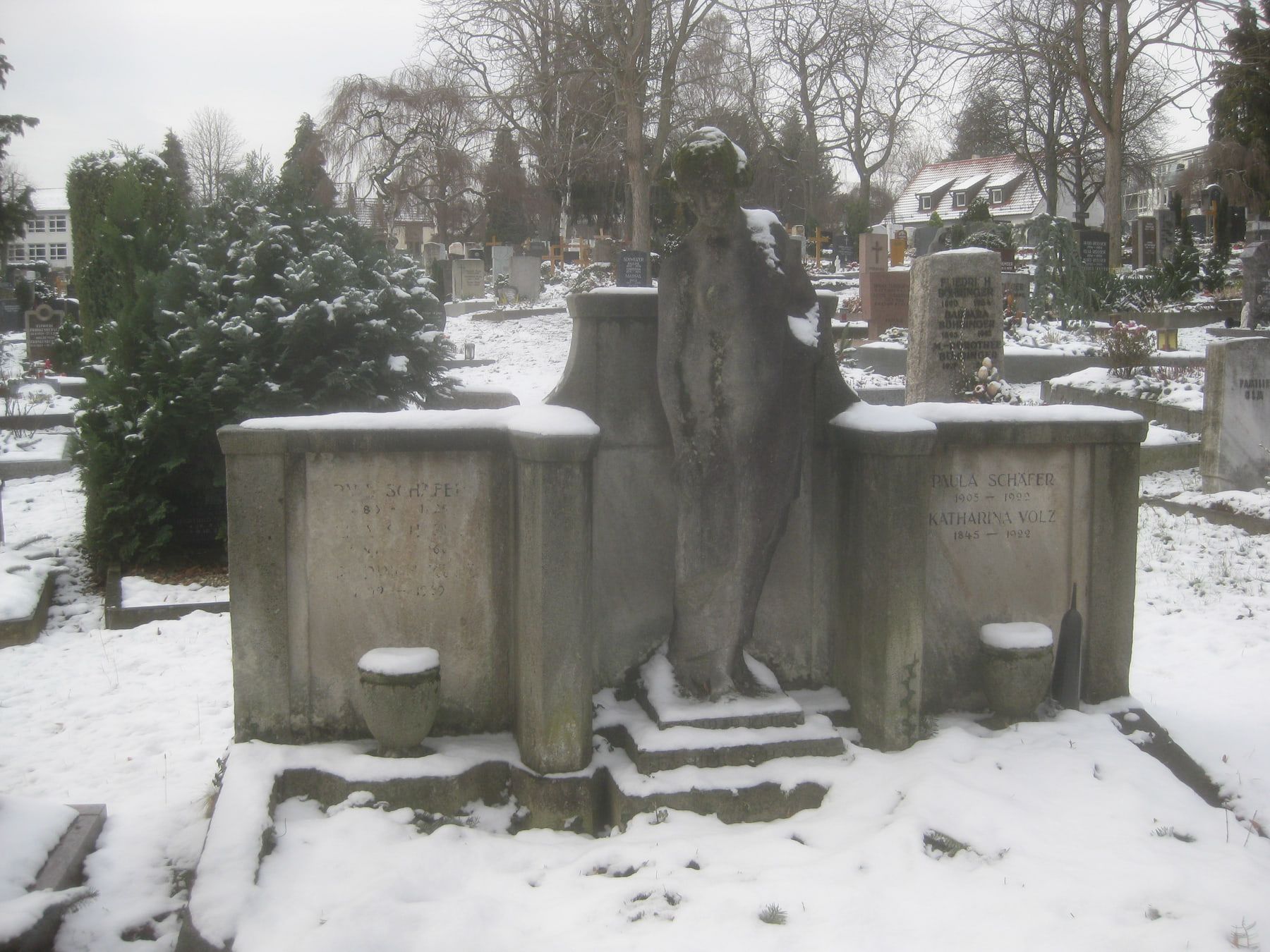 Monumentale Grabanlage mit dunkler Steinfigur vor verschneiten Grabfeldern auf Bergfriedhof Stuttgart